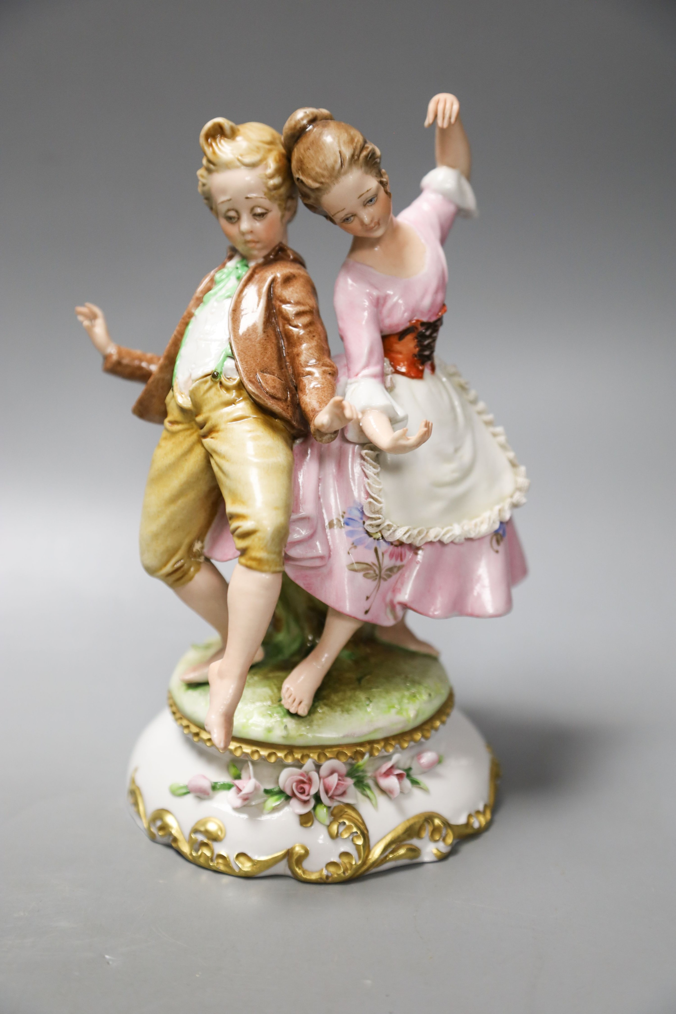 A Luigi Fabris porcelain figure of a lady wearing a crinoline dress, holding baskets of flowers, and two other figural groups (3)